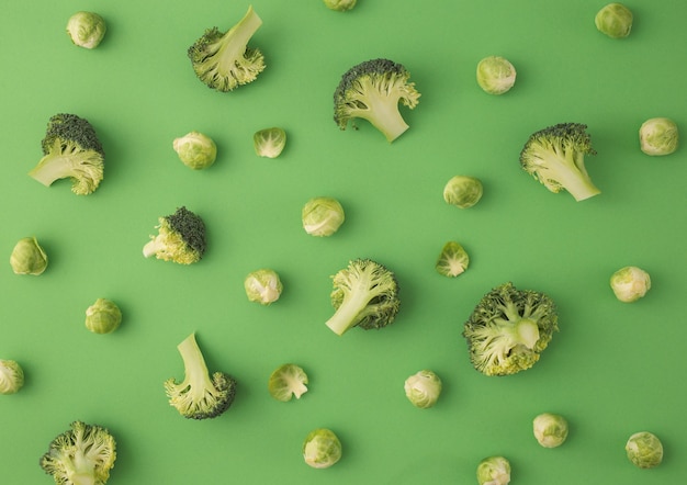 Green vegetables food pattern made of broccoli and Brussels sprouts on green background. Creative minimal flat lay design about nutrition, healthy eating, diets, vitamins. Top view