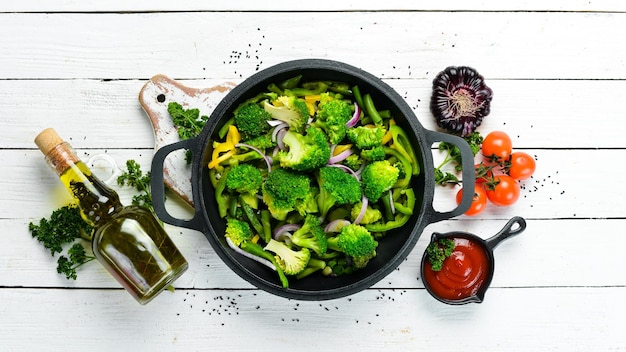 Green vegetables stewed in a frying pan Broccoli beans green peas Top view Free space for your text