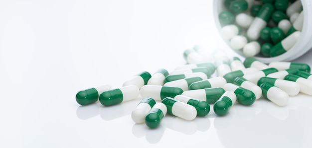 Green and white capsule pill spread out of pill bottle Healthcare and medicine Prescription drug