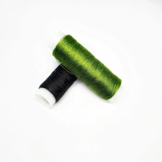 A green and white spool of thread with a black end.