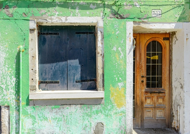 Green window on green old house wall in Burano Italy