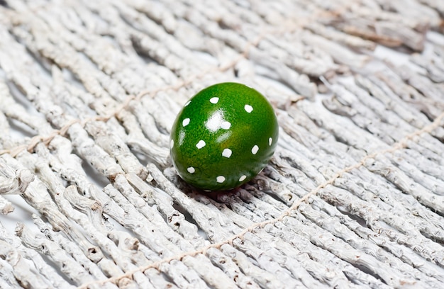 Green with white dots Easter egg on a wooden background.