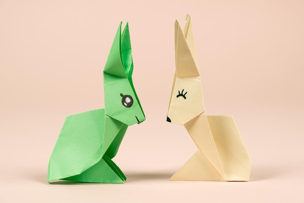 A green and yellow origami rabbits on a beige background