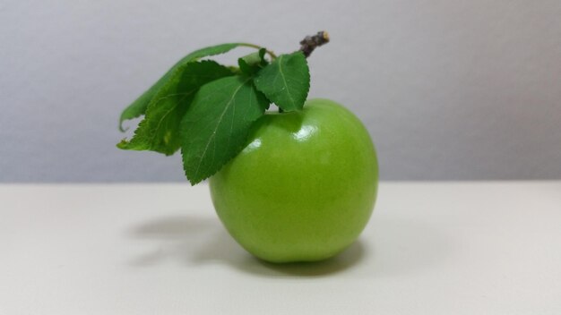 Photo greengage plum with leaves under studio lights from side view