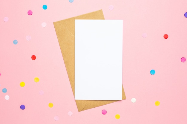 Greeting card and color confetti on pink table with space for text. 