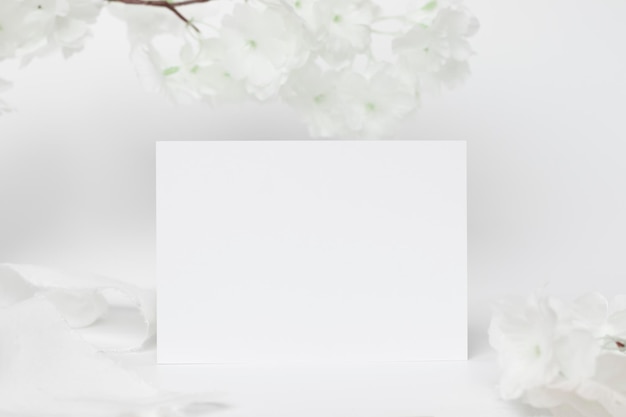 Greeting card mock up decoration with white flower Front view Blank paper card on a wood plate and white background