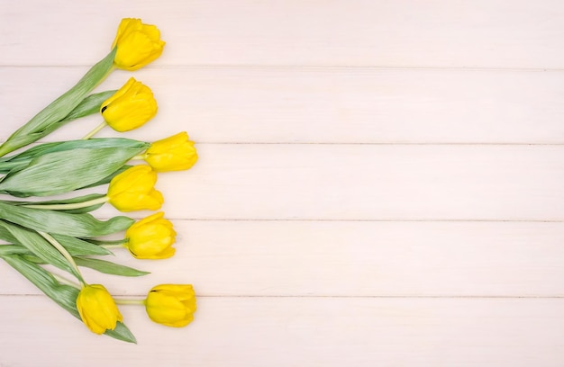 Greeting card for spring holidays bouquet of yellow tulips on wooden background with copy space