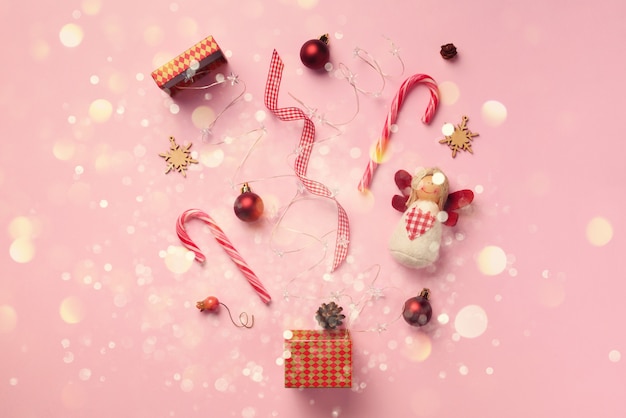 Greeting card with snow, lights bokeh for New year party. Christmas gifts, decorative elements and ornaments on pink background. 