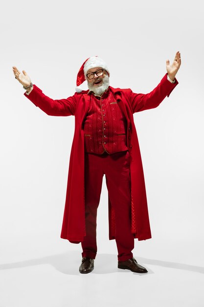 Photo greeting man. modern stylish santa claus in red fashionable suit isolated on white background. looks like a rockstar. new year and christmas eve, celebration, holidays, winter's mood, fashion.