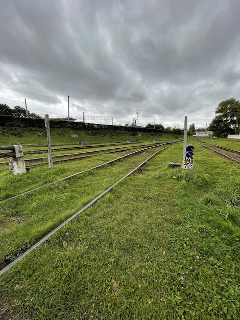 Grey autumn sky over green grass with railroad tracks