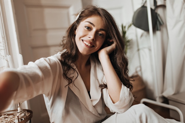 Grey eyed woman in white blouse taking selfie