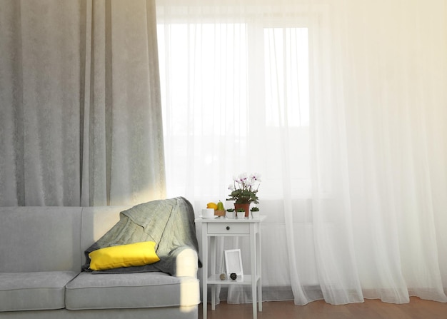 Grey sofa and small table with flowers on curtain background