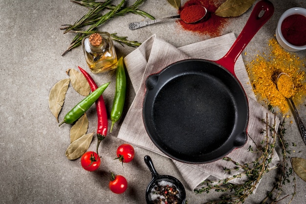 Photo grey stone culinary surface with empty black pan and selection of spices and seasonings