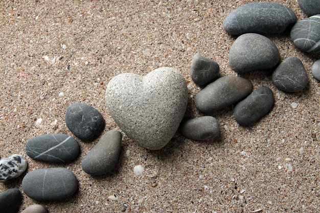 Grey stone in shape of heart on sand background