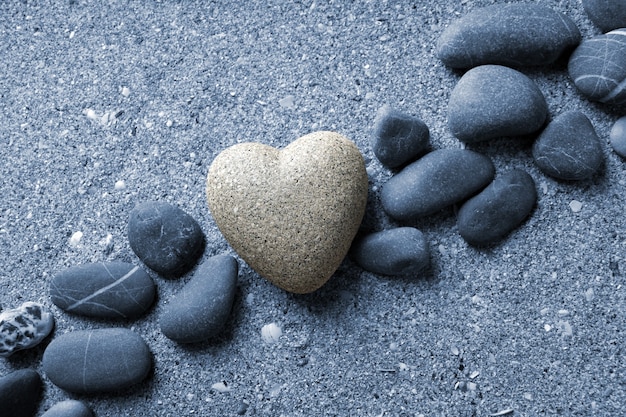 Grey stone in shape of heart, on sand surface