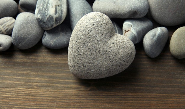 Grey stone in shape of heart on wooden background