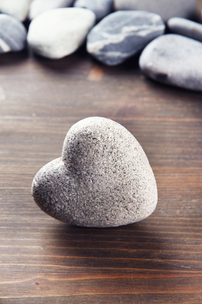 Grey stone in shape of heart, on wooden table