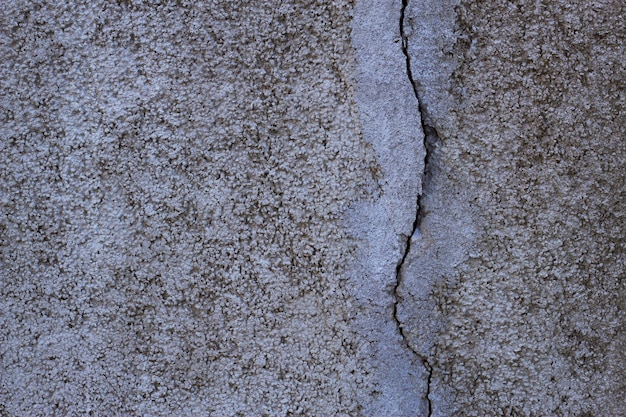 Grey textured wall surface with deep crack