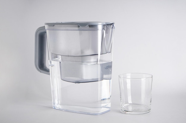 Grey Water filter jug and a glass of water on a grey background closeup