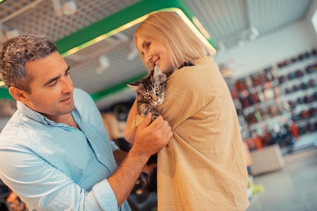 Greyhaired husband smiling while looking at wife holding cat