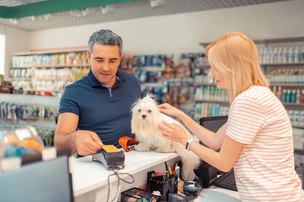 Greyhaired man paying for white dog for daughter by card