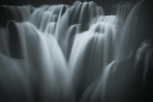 Greyscale closeup shot of the pouring foamy cascades of a waterfall