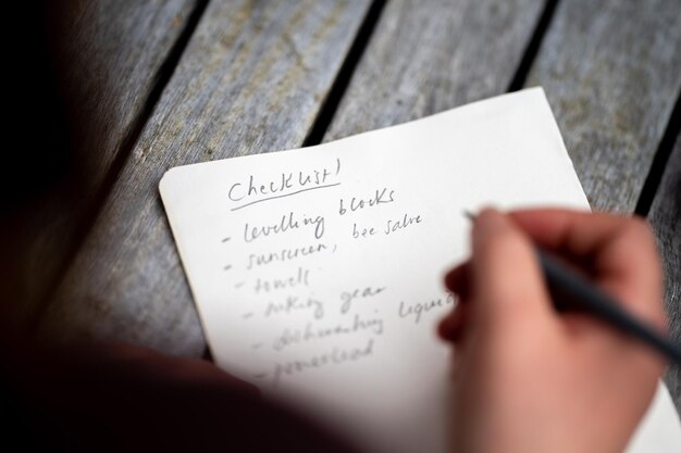 Gril writing a camping list in a piece of paper writing a check list with a pencil