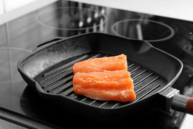 Grill frying pan with slice of salmon on induction stove