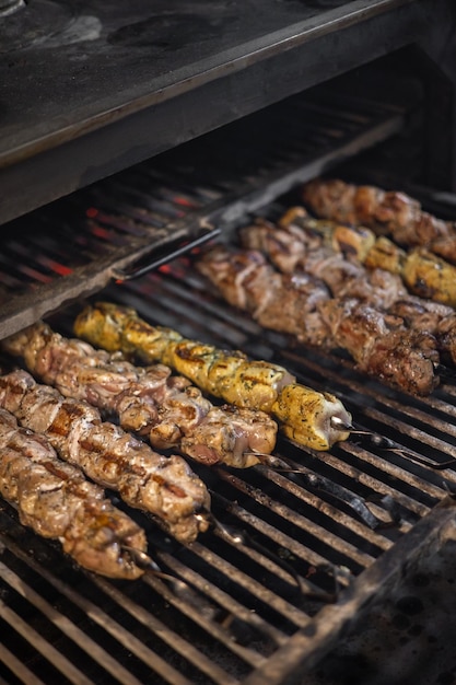 Grill view with chickens Chickens and sausages are fried on the grill Spending time together with the family at the grill Social meetings friends Red gril with kindling and coal