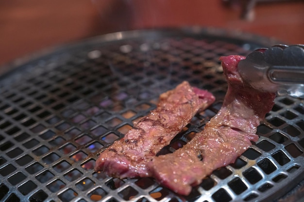 A grill with a knife on it and a steak on it.