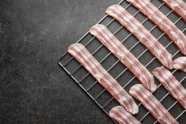 Grill with strips of bacon on table