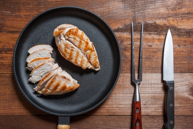 Grillad chiken fillet on pan, cooked meat. Wooden background, flat lay