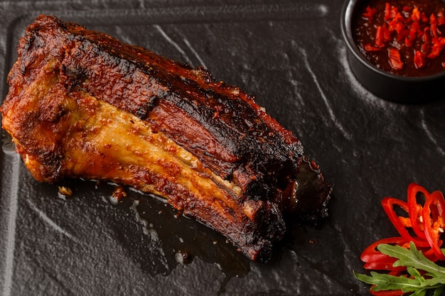 Grilled and barbecue hot pork ribs with hot chilli pepper and hot sauce on black stone