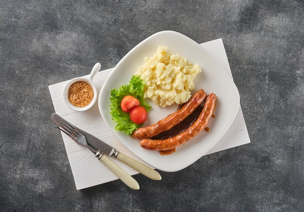 Photo grilled beef bratwurst with mash potato on white plate over grey background bbq beef sausages