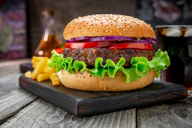 Grilled beef burger with tomatoes onions and fried potatoes