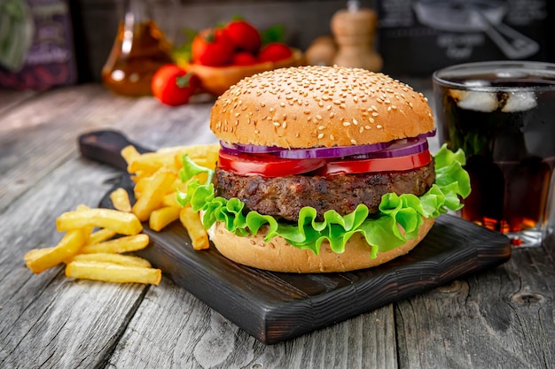 Grilled beef burger with tomatoes onions and fried potatoes