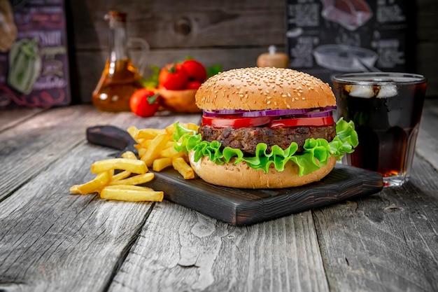 Grilled beef burger with tomatoes onions and fried potatoes