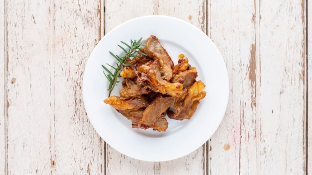 Grilled beef fillet steak meat with oregano and rosemary in white plate on white wood texture background top view light and airy food photography