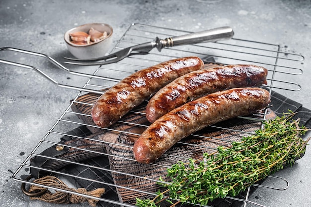 Grilled beef and lamb meat sausages with rosemary herbs on grill. Gray background. Top view.