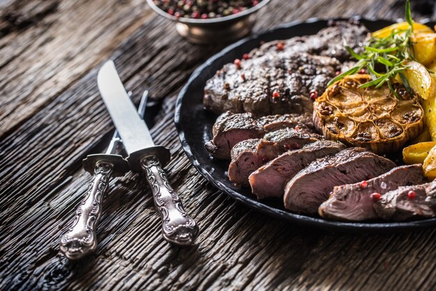 Grilled beef Rib Eye steak with garlic american potatoes rosemary salt and spices.