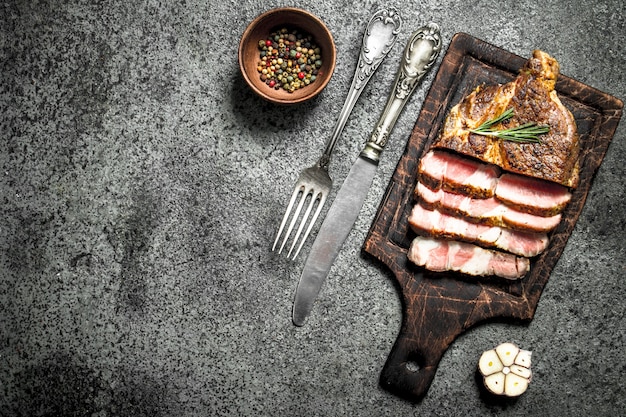 Grilled beef steak on a blackboard with spices. On rustic background.