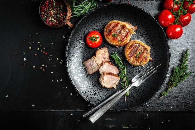 Grilled beef steak by chef hands on black background. filet Mignon beef tenderloin steak covered bacon with spices. top view.