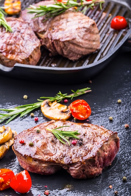 Grilled beef steak on slate board with salt pepper and rosemary.