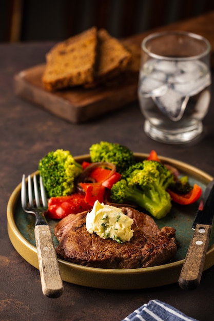 Grilled Beef steak with garlic butter and vegetables. Meat with grilled bell pepper, broccoli and onions.