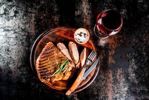 Grilled beef steak with spices on cutting board, with and red wine glass. Copy space top view