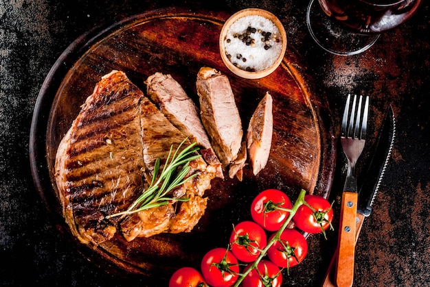 Grilled beef steak with spices on cutting board, with and red wine glass.  copyspace top view