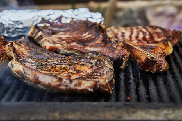 Grilled beef steaks with grill smoke. BBQ party.