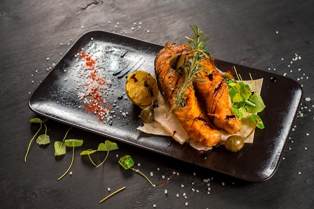 Grilled big fish steak on the black wooden background