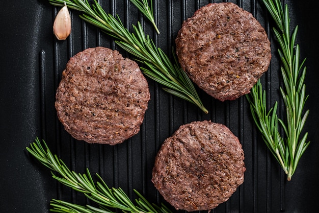 Grilled burger meat patties with spices on grill pan Black background Top view