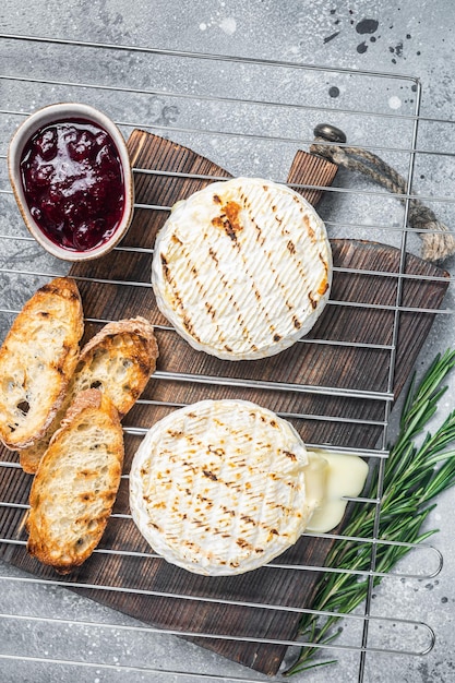 Grilled Camembert cheese on grill with cranberry sauce and toast Gray background Top view